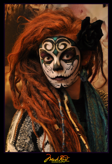 red haired woman in a full face painting that is a detailed skull